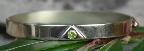 Zilveren Lemuri armband met in de driehoek een groene briljant ingelegd.