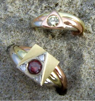 Twee driekleur gouden ringen: n met rode briljant en 3 triljanten ingelegd, de ander met een groene briljant.
